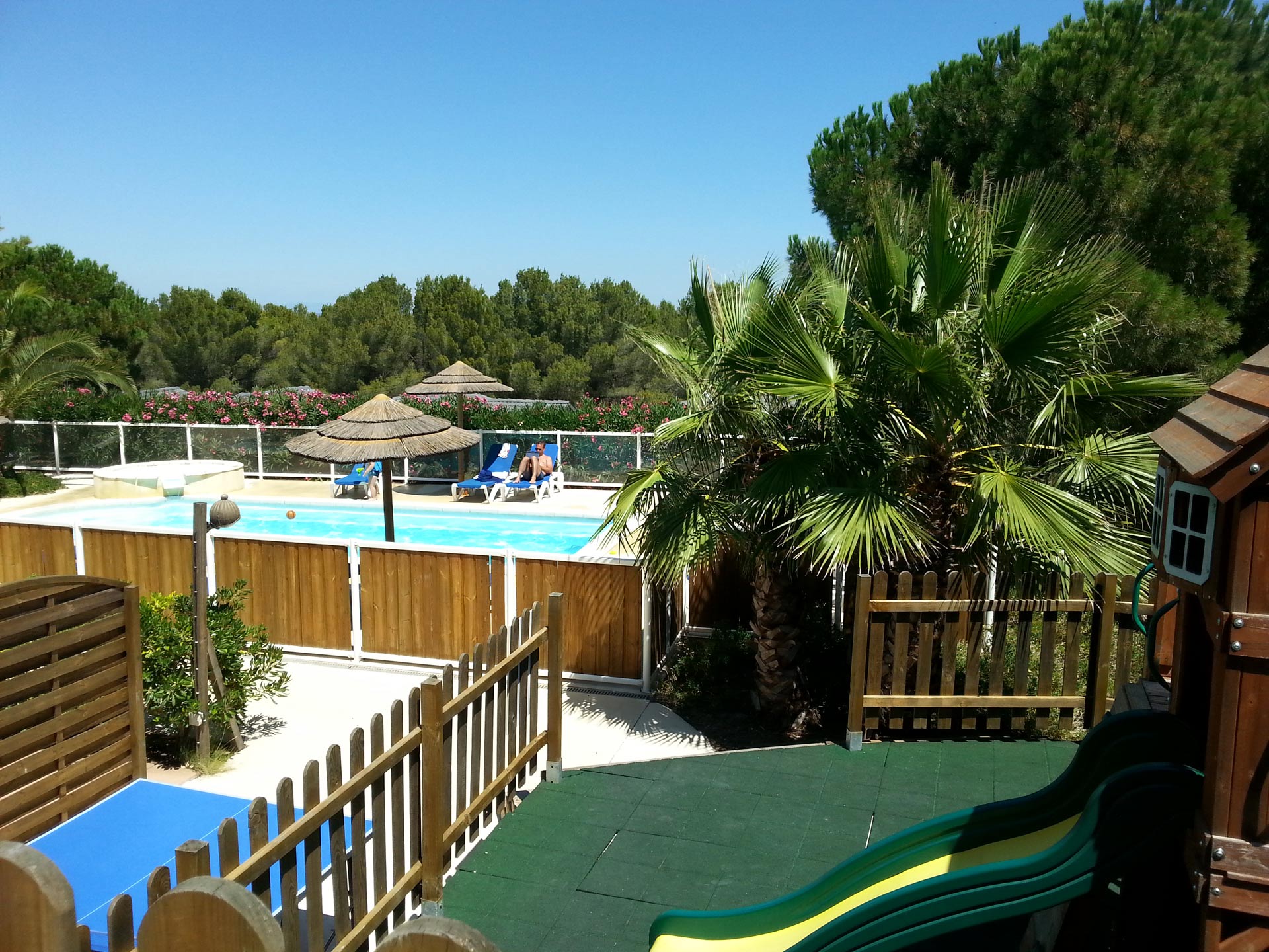Aire de jeux sécurisée et vue sur la piscine chauffée du parc résidentiel de loisirs Les Hauts de Baldy au Cap d'Agde